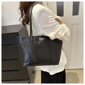 Side view of a large black leather tote bag worn over the shoulder for daily commute
