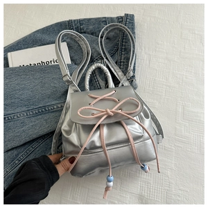 Detail of silver metallic PU backpack with pink bow weaving and bead accents