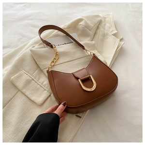 Close-up of brown crescent bag featuring gold D-ring hardware and leather chain strap