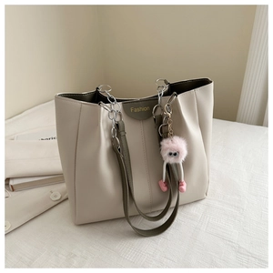 Dettaglio borsa tote crema con manici verde oliva e ciondolo di peluche rosa