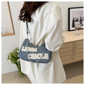 Detail of vintage blue denim hobo bag with LANN CIRCLE letter patch and metal chain strap