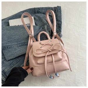 Close-up of pink mini backpack featuring ballet-style ribbon bow and PU leather texture