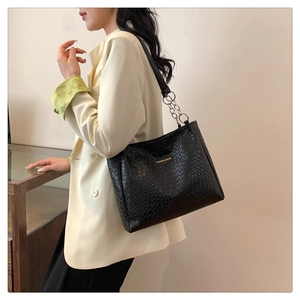 Close-up of black woven texture tote bag with gold logo and silver chain strap detail