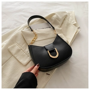 Detail of black leather hobo bag with gold U-shaped magnetic buckle and metal chain strap