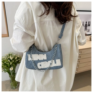 Detail of light blue denim shoulder bag with silver chain and Runn Circle text patch