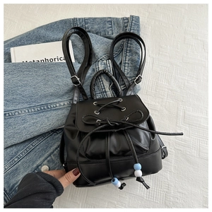 Detail of a black mini PU leather backpack with bow drawstrings and blue-white beads