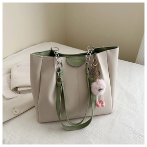 Dettaglio della borsa tote color-block con finiture verde salvia e ciondolo