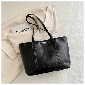 Close-up of black leather tote bag with vertical stripes on a stylish beige blazer