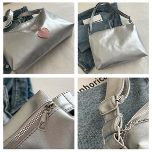 Detail view showing silver metallic PU bag with wing embroidery and pink heart charm