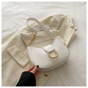 Detail of white crescent underarm bag with gold horseshoe buckle and chain strap accent