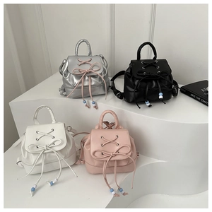 Detail showing four mini backpacks in silver, black, white, and pink with drawstring bows