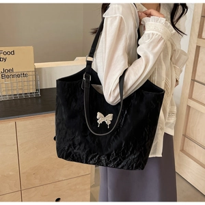 Close-up of black velvet tote bag with pleated texture and silver butterfly ornament