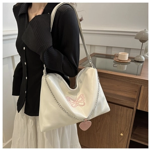 Detailed close-up of white tote bag with pink butterfly embroidery and heart charm