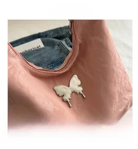 Close-up of pink textured fabric with silver butterfly ornament and metal zipper detail