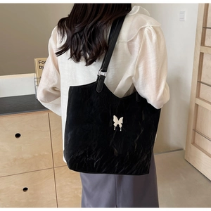 Close-up of black velvet tote bag featuring a white butterfly ornament and pleated texture