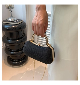 Dettaglio pochette da sera nera glitterata con manico dorato e chiusura in strass
