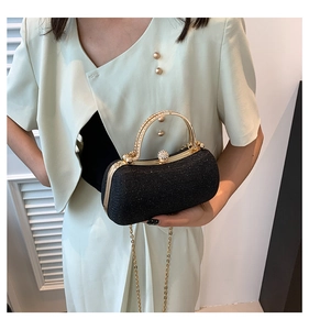 Détail de pochette de soirée noire pailletée avec poignée dorée et fermoir strass