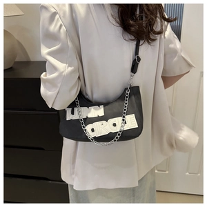 Detail view of black crescent shoulder bag with chain strap on a fashion model