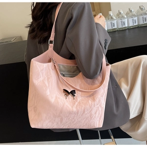 Detail of light pink pleated tote bag featuring a metallic butterfly logo and slim straps
