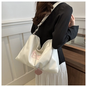 Detailed close-up of white PU leather shoulder bag with pink butterfly embroidery and chain