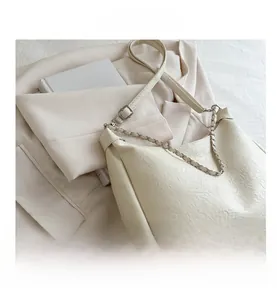Close-up of white pleated leather texture on bag with silver chain on beige blazer