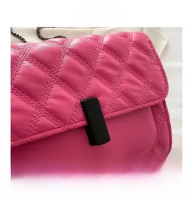 Close-up of bright pink quilted leather handbag featuring a black rectangle twist lock