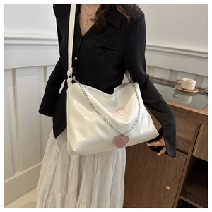 Detail of white tote bag with pink butterfly embroidery and silver chain accessory
