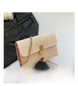 Detail of woven straw bag showing gold twist lock closure and chain leather shoulder strap