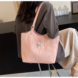Detail of pink velvet tote bag featuring a silver butterfly charm and pleated texture