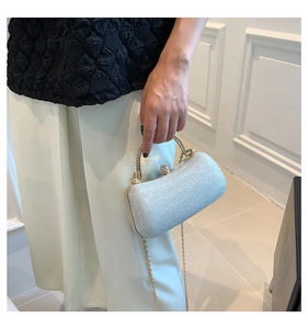 Pochette argentée à paillettes avec fermoir en cristal et chaîne dorée tenue à la main