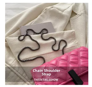 Detail view of fuchsia quilted chain bag with dark grey metal strap and black clasp