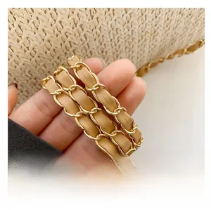 Close-up of light brown leather and gold metal chain strap on a straw woven bag