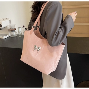 Pink velvet tote bag with a metallic butterfly charm in a minimalist cafe setting