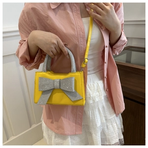 Sac à main jaune avec nœud scintillant porté par un mannequin en rose et jupe en dentelle