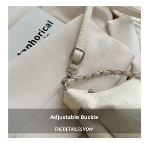 Detail of adjustable buckle and silver metal chain on milk white faux leather bag