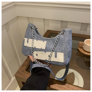 Detail showing denim crescent bag with UNN CIRCLE patch and metal chain strap
