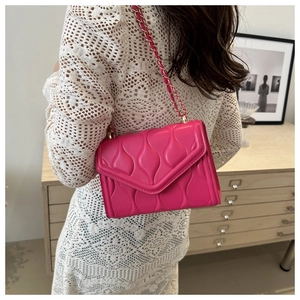 Quilted rose red chain square bag shown on model with white dress for elegant look