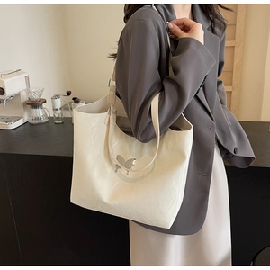 Detail of off-white velvet tote bag with butterfly pendant and pleated texture