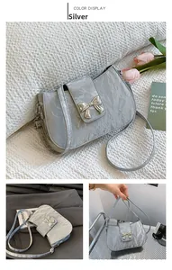 Nahaufnahme der silbernen Schultertasche mit Faltenoptik und Metallschleife als Verschluss