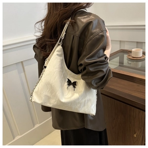 Detail of creamy white crossbody bag with pleated leather texture and butterfly buckle