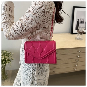 Close-up of pink quilted crossbody bag with gold chain strap worn by a model