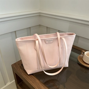 Pink waterproof nylon tote bag with leather logo on a rustic dark wooden tabletop