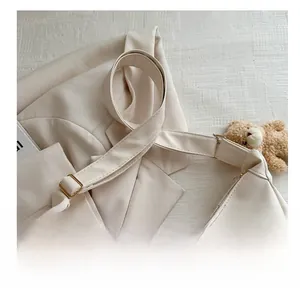 Detail of adjustable cream leather shoulder strap with gold buckle on a stylish bag