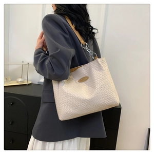 Close-up of beige woven texture tote bag with brown leather and chain shoulder strap