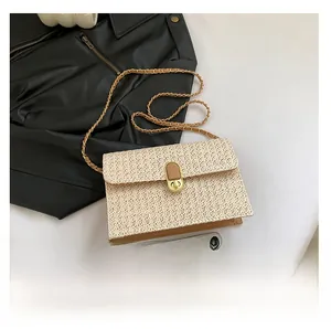 Detailed view of woven crossbody bag with gold buckle next to a smartphone for size comparison