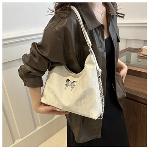 Detail of white tote bag with metallic butterfly buckle and leather chain strap