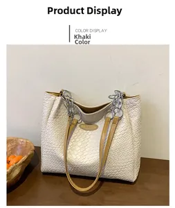 Detail of woven texture tote bag with leather logo patch and metal chain link straps