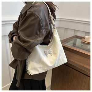 Detail of white pleated handbag with silver butterfly buckle on trendy leather outfit