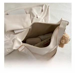 Spacious interior of the cream shoulder bag showing storage for phone and cosmetics