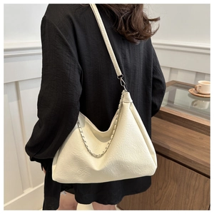Detailed view of cream white pleated shoulder bag featuring a silver metal chain accessory